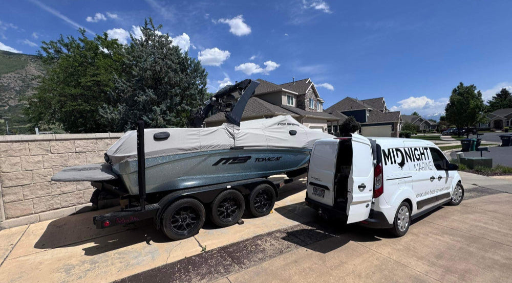 White van with 'Midnight Marine' branding with a boat on a trailer in a residential area.