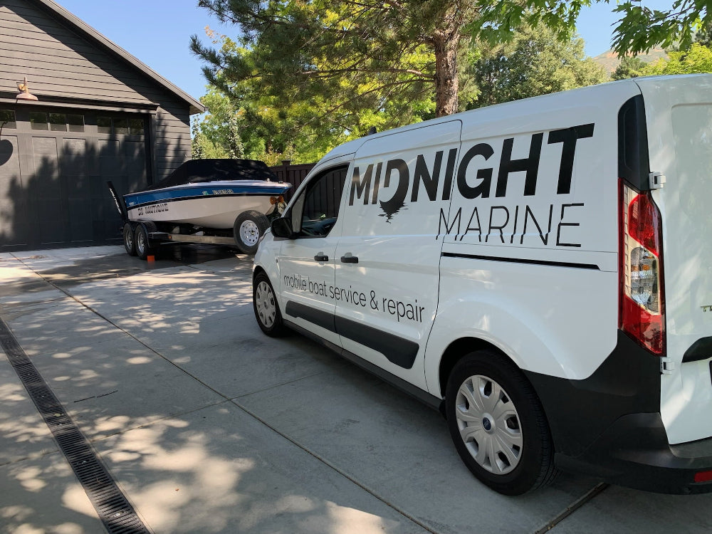 White van with 'Midnight Marine' branding parked in a driveway with a boat in the background.