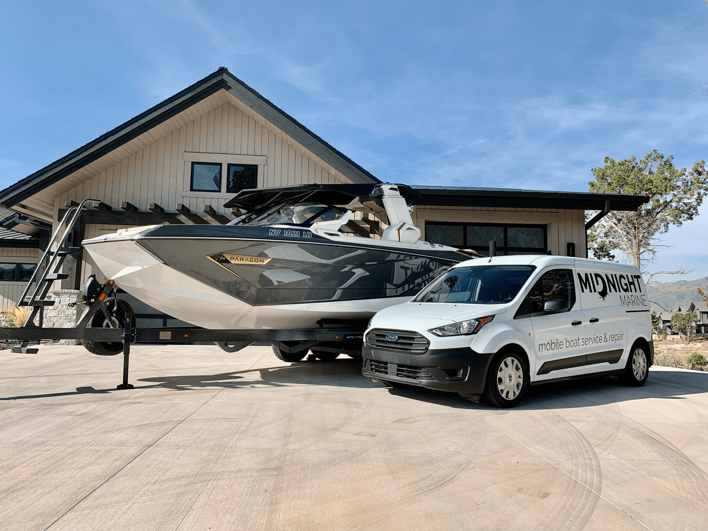 Van with 'Midnight Marine' branding with a boat on a driveway.